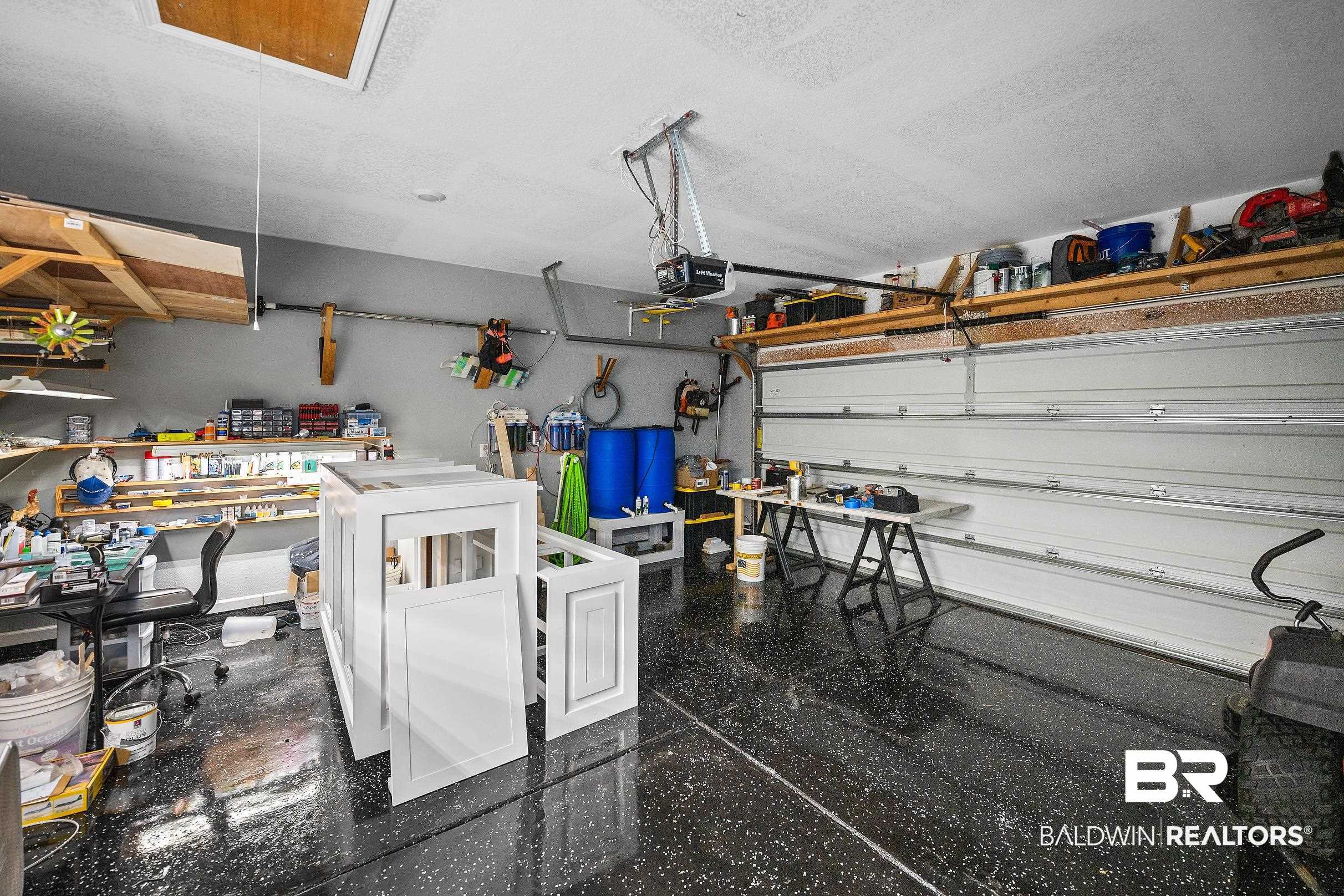 23997 Veranda Circle Elberta, AL 36530 - Photo 20 of 28 Spacious garage featuring a durable epoxy floor finish, overhead storage shelving, and a prominent garage door