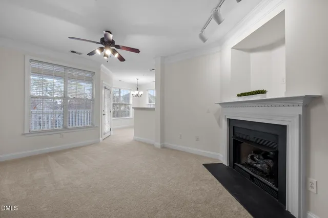 a view of a livingroom with a fireplace a ceiling fan and windows