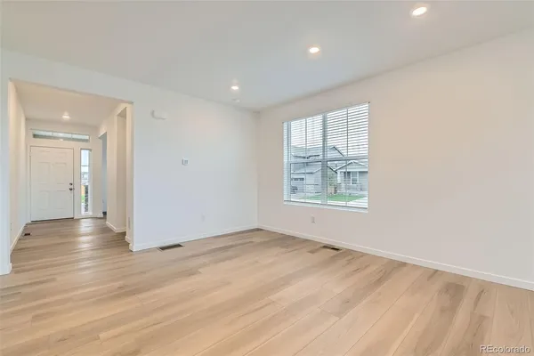 an empty room with wooden floor and windows