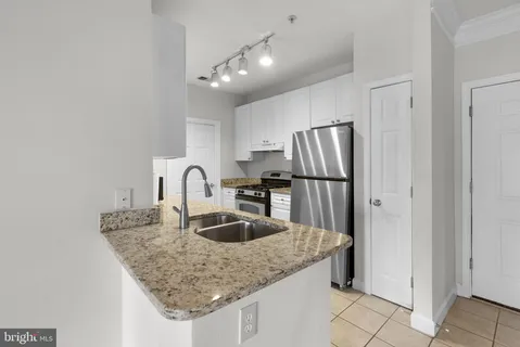 a kitchen with granite countertop a refrigerator and a sink