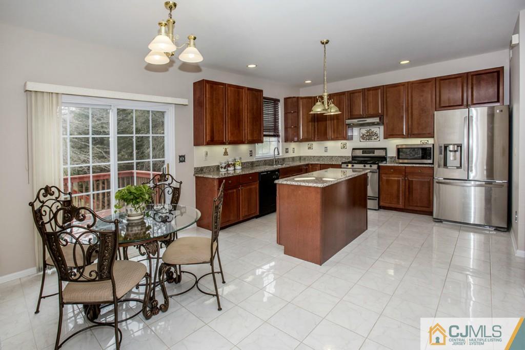 27 Timber Ridge Road North Brunswick, NJ 08902 - Photo 9 of 25 a kitchen with stainless steel appliances granite countertop a stove top oven a refrigerator a sink dishwasher a dining table and chairs with wooden floor