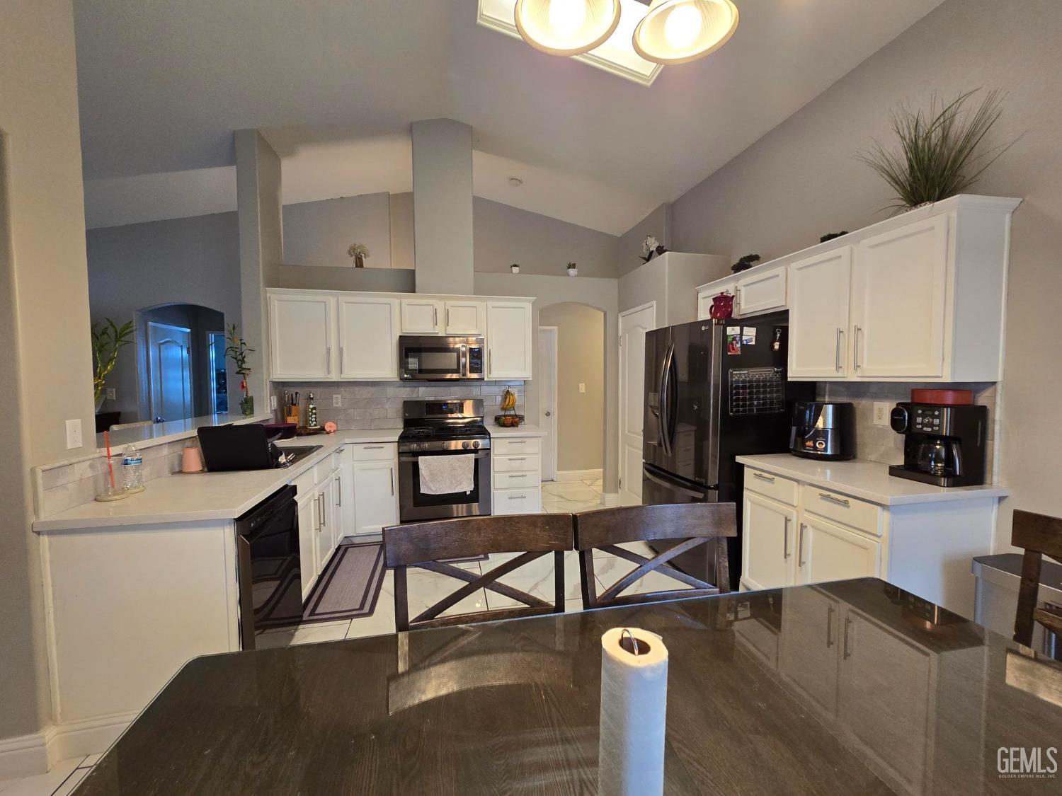 Undisclosed Address Bakersfield, CA 93307 - Photo 4 of 19 a kitchen with a refrigerator a stove cabinets and a dining table