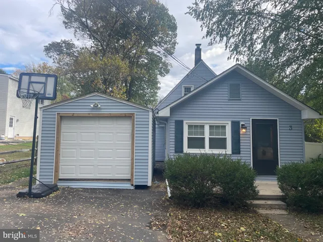 a view of a house with a yard plants and large tree