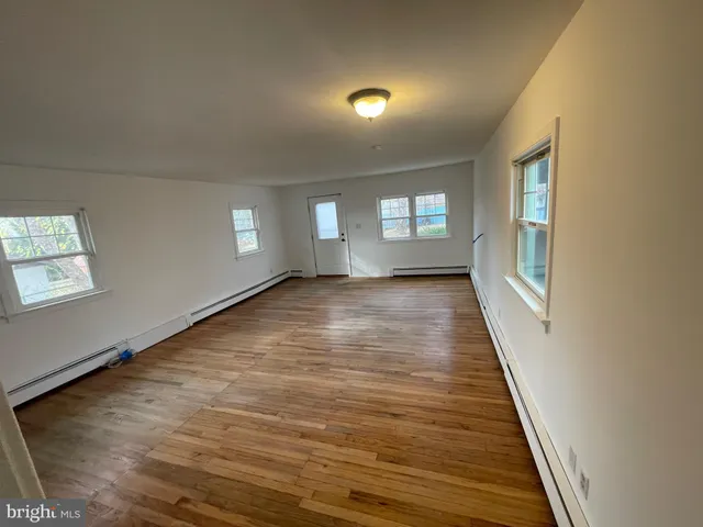 a view of an empty room with wooden floor and windows