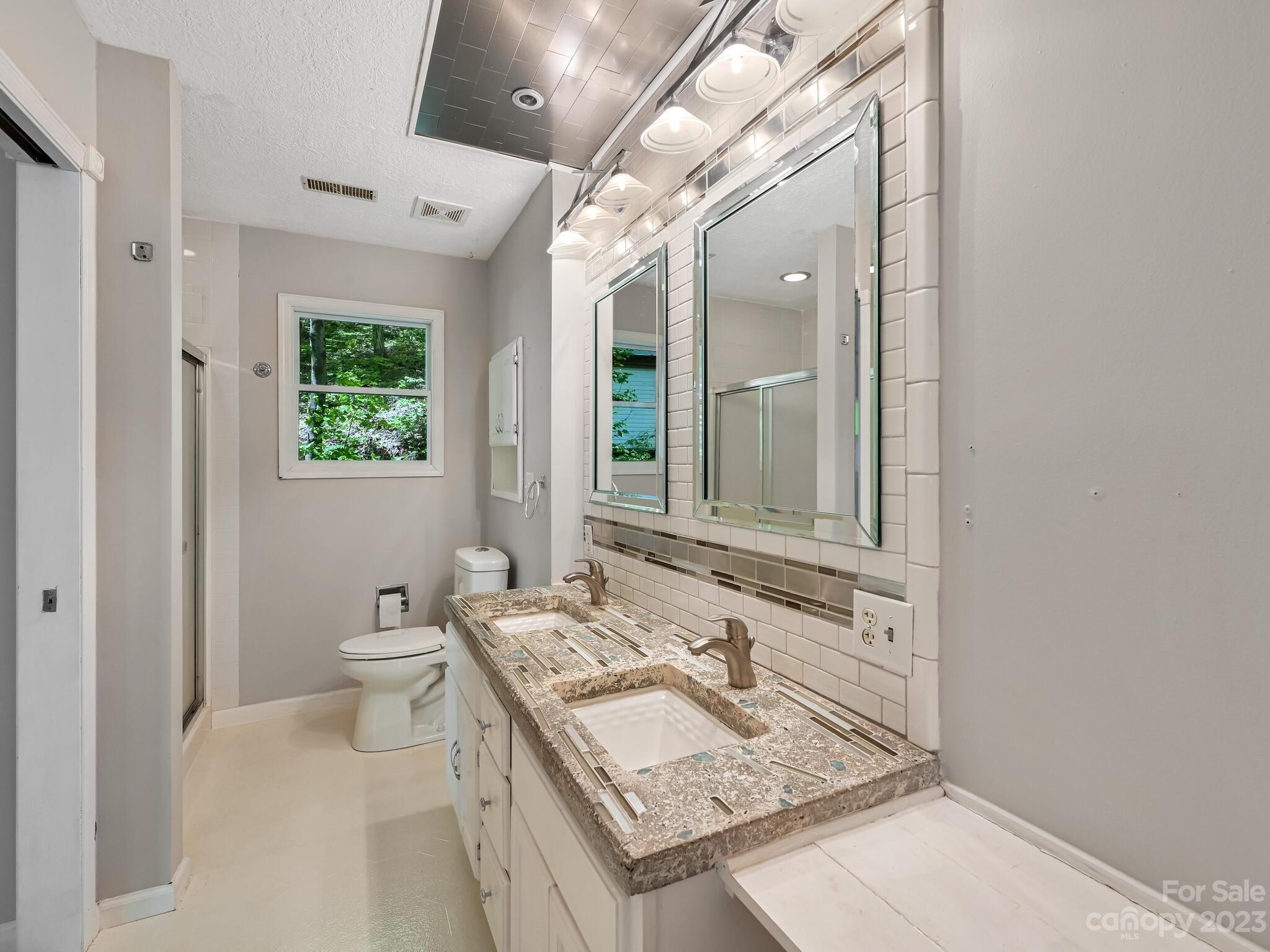 843 North Fork Road Barnardsville, NC 28709 - Photo 19 of 37 a bathroom with a granite countertop sink mirror vanity and a toilet