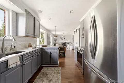 a kitchen with stainless steel appliances a stove a sink dishwasher a refrigerator oven a sink dishwasher and white cabinets next to a window