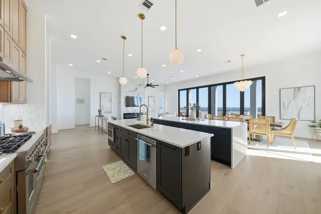 a large kitchen with stainless steel appliances a large counter top a stove a chimney a sink and a large window