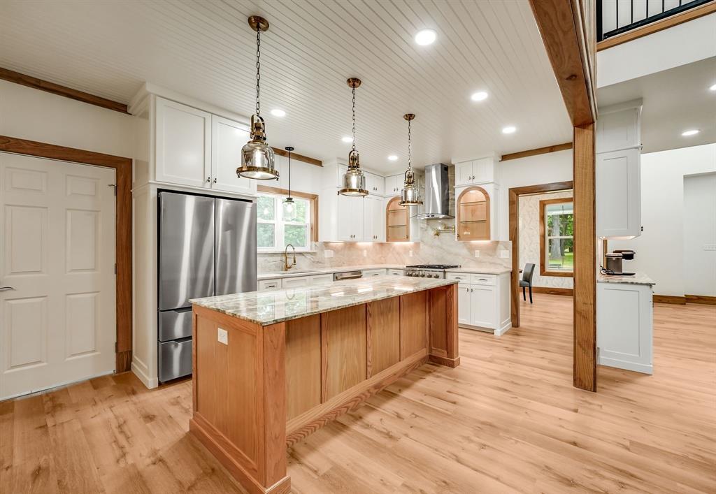 1037 Harrison Road Denison, TX 75021 - Photo 4 of 39 Kitchen featuring a natural wood-finish island with a light-toned countertop, stainless steel appliances, white cabinetry, and wood-finish flooring