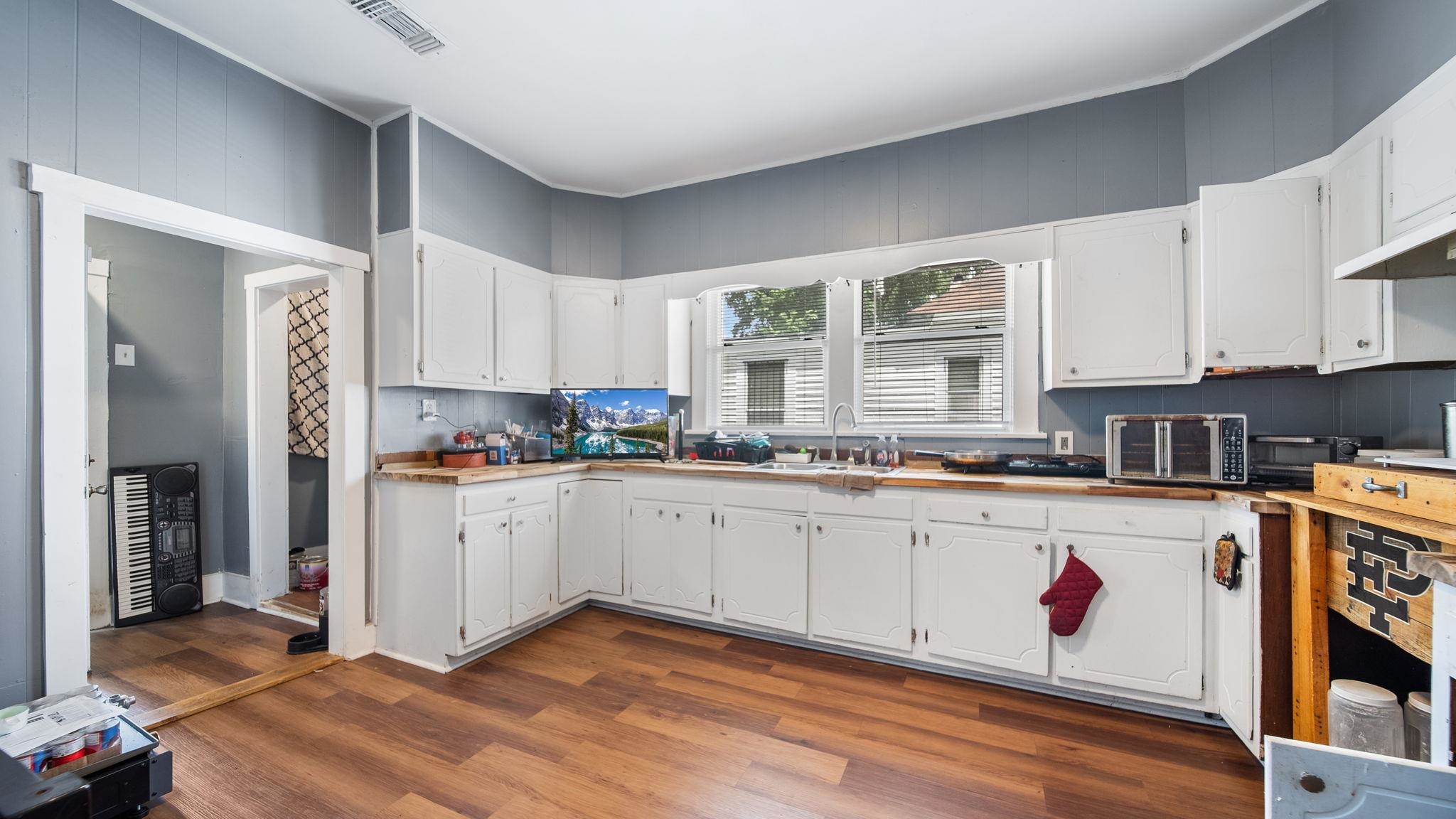 659 Decatur Street Memphis, TN 38107 - Photo 11 of 24 Kitchen featuring wood-finish flooring, white cabinetry, light-toned countertops, and painted panel walls