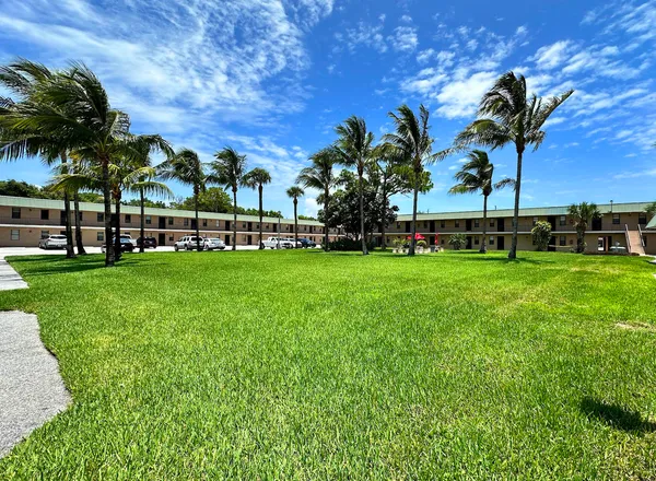 a view of a house with a big yard and palm trees