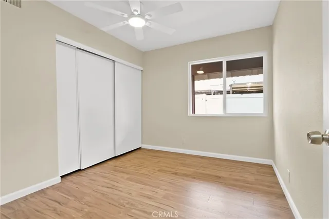an empty room with wooden floor closet and windows