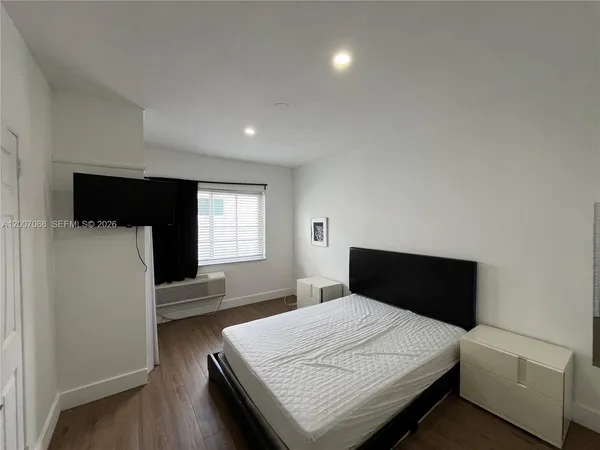 a bedroom with a bed and a flat tv screen on a dresser
