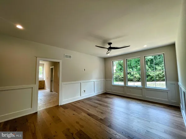 an empty room with wooden floor and windows
