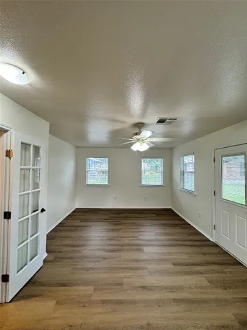 an empty room with wooden floor and windows