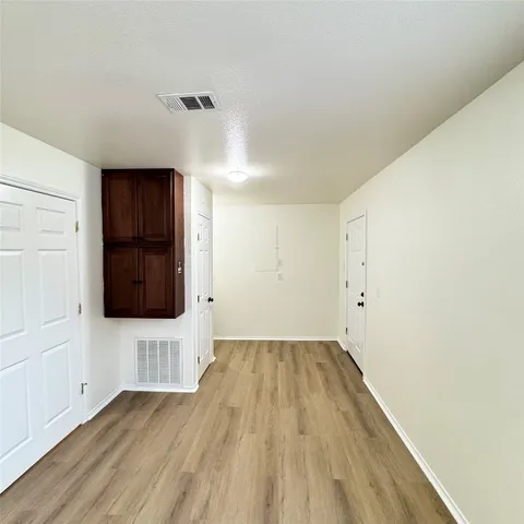 a view of hallway with wooden floor and cabinet