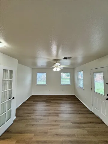 a view of an empty room with wooden floor and a window