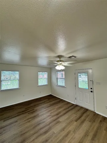 an empty room with wooden floor and windows