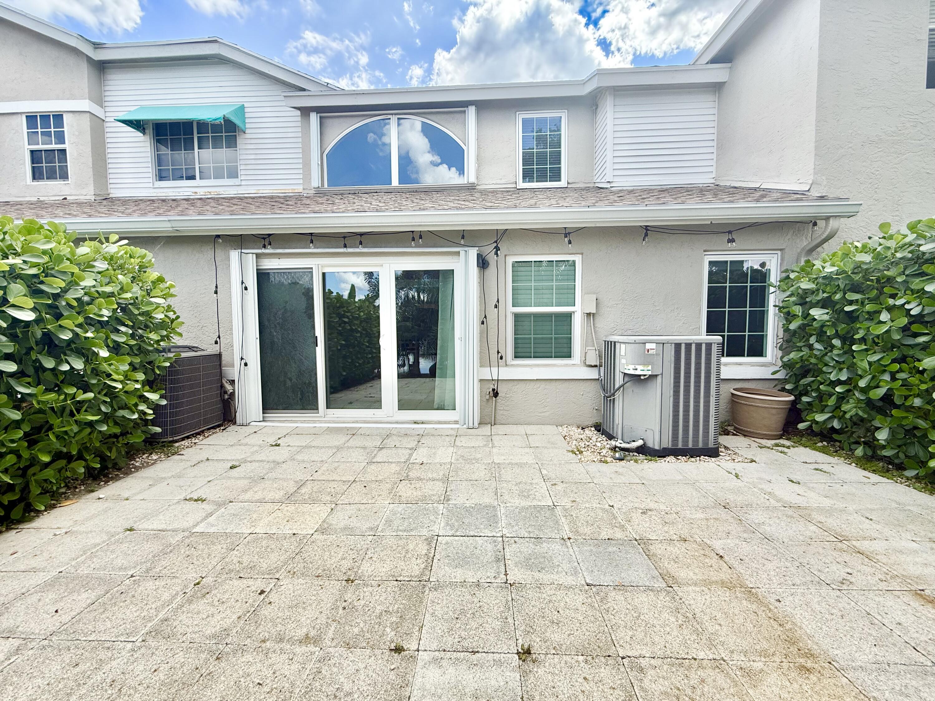 9190 Boca Gardens Parkway, Unit B Boca Raton, FL 33496 - Photo 12 of 35 a view of white house with potted plants and a large window