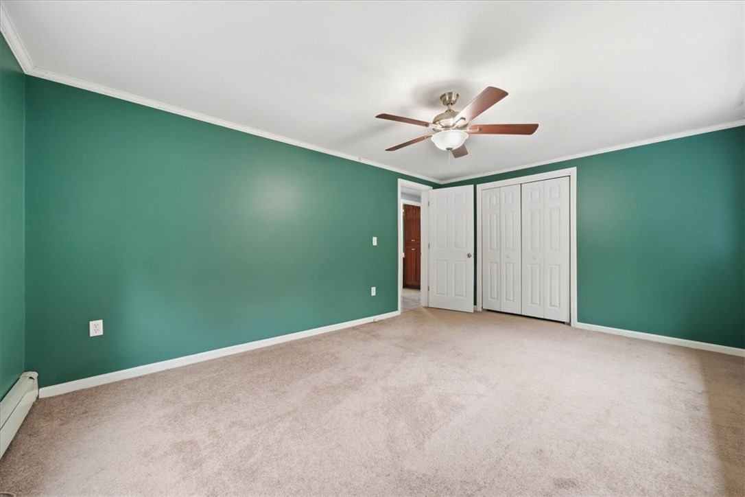 214 Anan Wade Road Glocester, RI 02857 - Photo 20 of 50 A comfortable primary retreat with soft carpeting, crown molding, ceiling fan and windows on two sides for exceptional natural light.