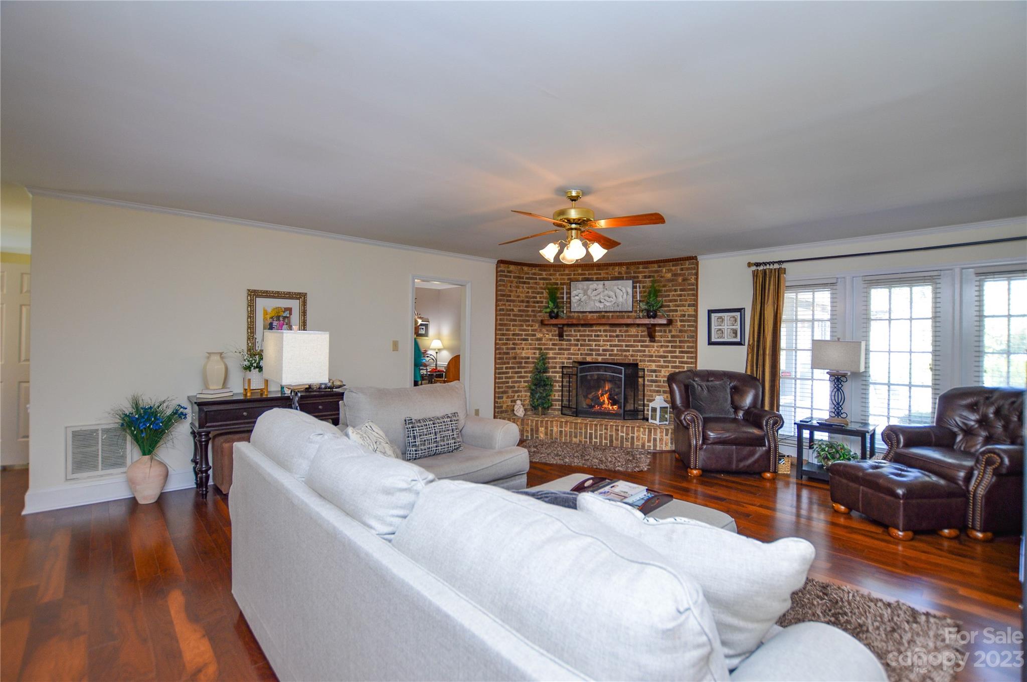 5215 Rocky River Road Charlotte, NC 28215 - Photo 6 of 33 a living room with furniture a fireplace and a dining table with wooden floor