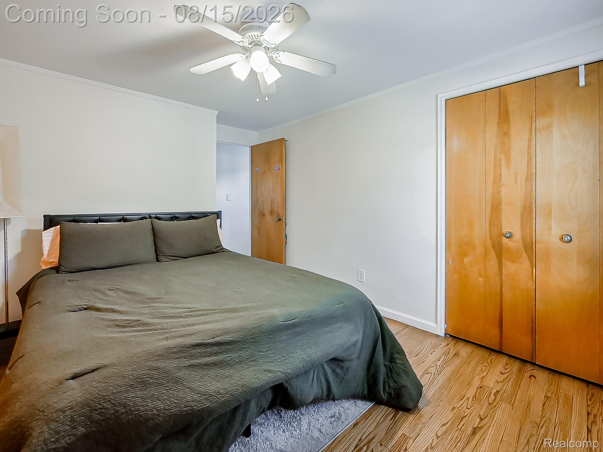 21131 Harvard Road Southfield, MI 48076 - Photo 12 of 33 Spacious primary bedroom featuring hardwood flooring, a ceiling fan with integrated lighting, and dual wood-finish closet doors providing ample storage