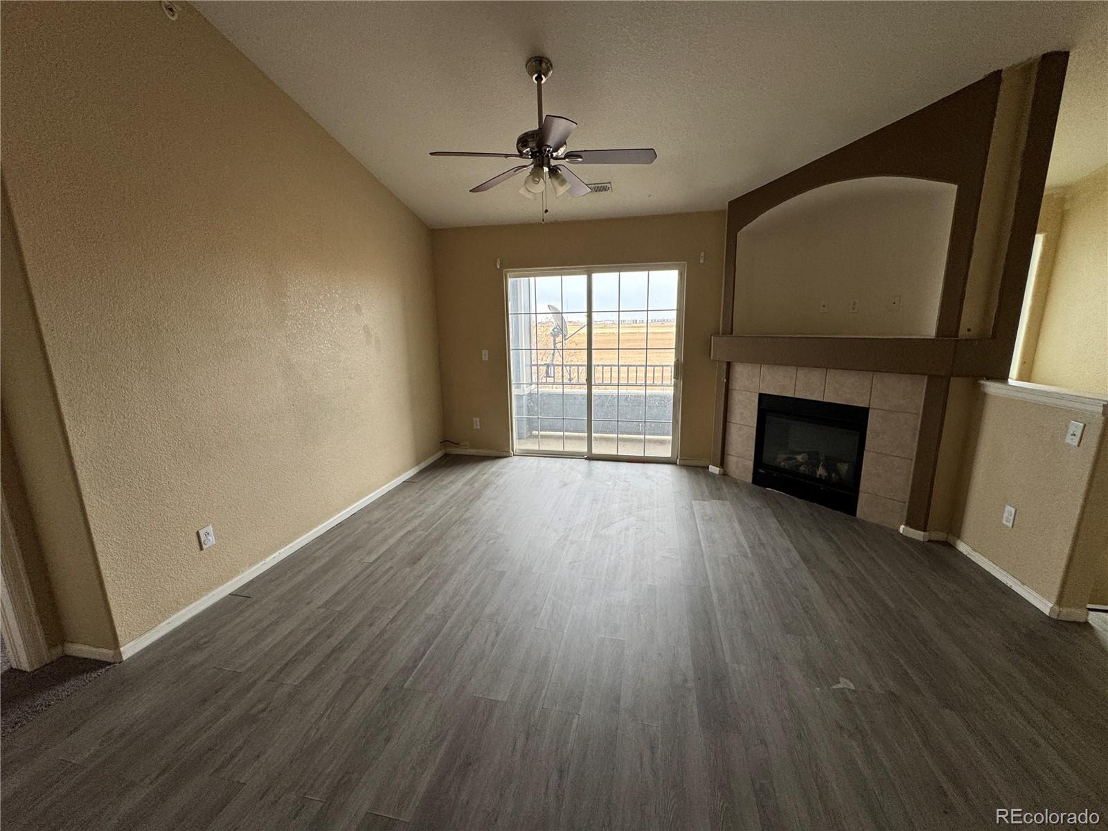 5255 Memphis Street, Unit 121 Denver, CO 80239 - Photo 3 of 9 an empty room with wooden floor fireplace and windows