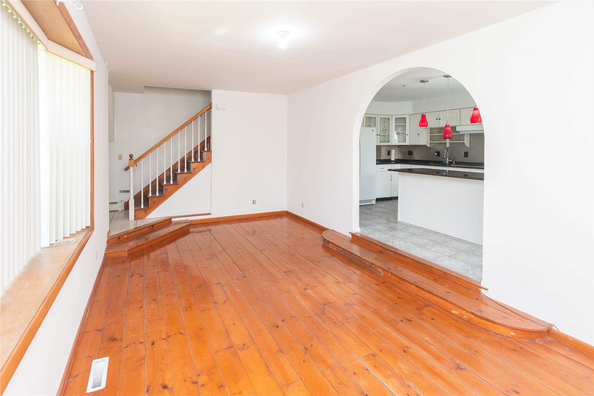 57 East Rock Cut Road Walden, NY 12586 - Photo 6 of 27 Unfurnished living room with arched walkways, stairway, baseboards, light wood-type flooring, and baseboard heating