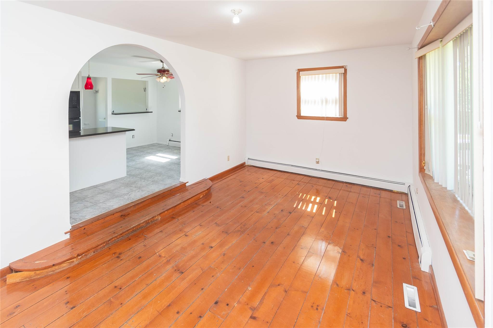 57 East Rock Cut Road Walden, NY 12586 - Photo 7 of 27 Empty room featuring a baseboard radiator, arched walkways, ceiling fan, and light wood-style flooring