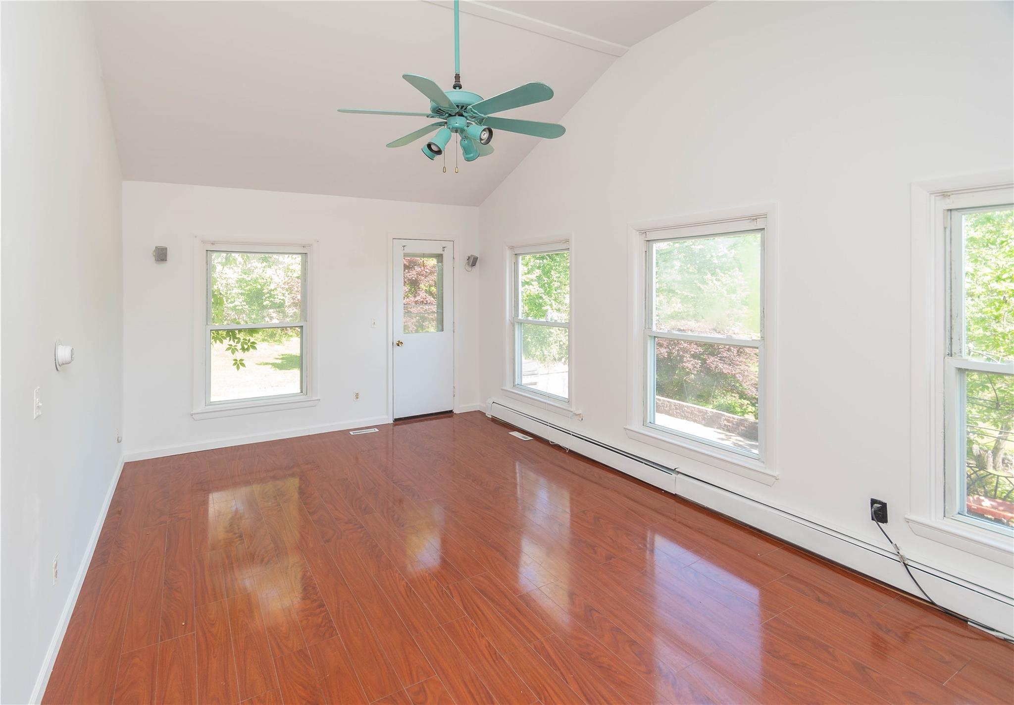 57 East Rock Cut Road Walden, NY 12586 - Photo 8 of 27 Unfurnished room with a baseboard heating unit, wood finished floors, baseboards, ceiling fan, and high vaulted ceiling