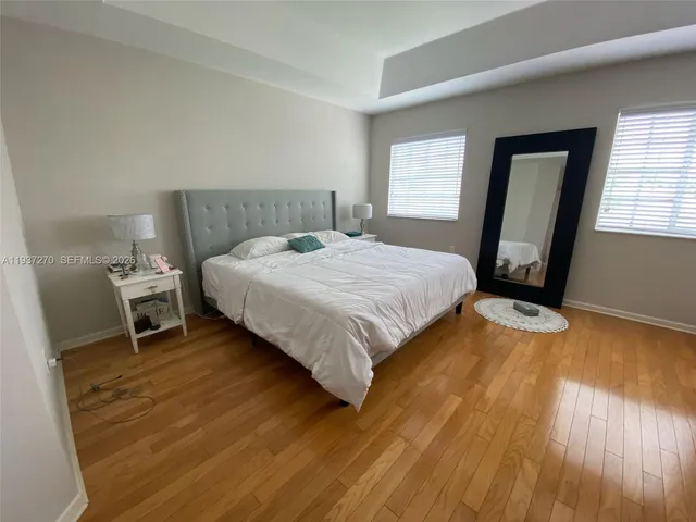 a bedroom with a bed a mirror on dresser and a wooden floor