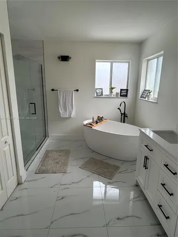 a spacious bathroom with a tub sink and mirror