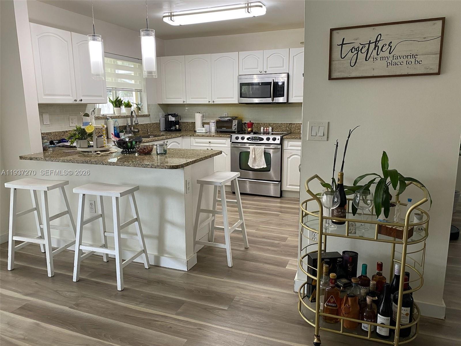 15442 Southwest 139th Street Miami, FL 33196 - Photo 7 of 27 a kitchen with stainless steel appliances kitchen island granite countertop a stove top oven a sink a dining table and chairs