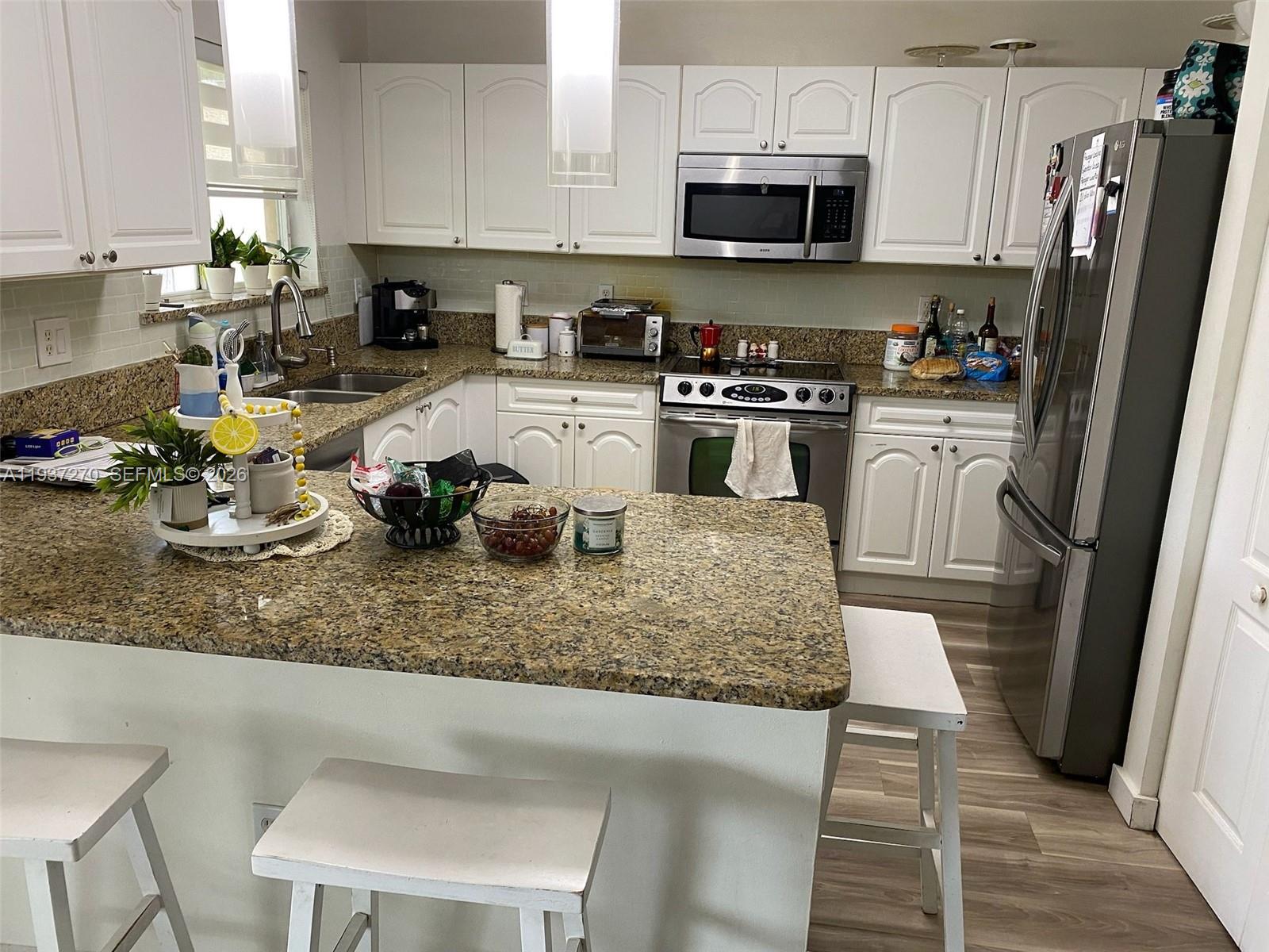 15442 Southwest 139th Street Miami, FL 33196 - Photo 8 of 27 a kitchen with sink a microwave and cabinets