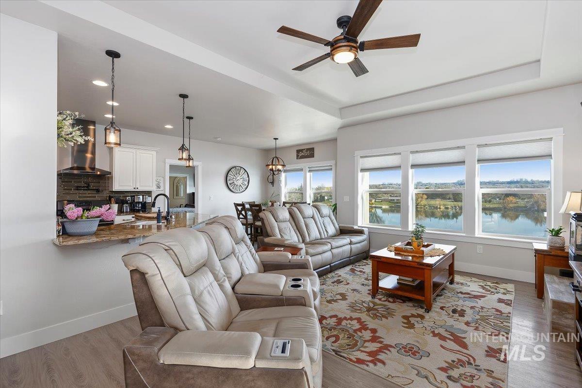 40 Bell Rapids Road Hagerman, ID 83332 - Photo 3 of 50 Living room with light wood-type flooring, a ceiling fan, a water view, a chandelier, and a raised ceiling