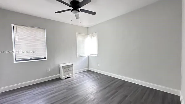 a view of an empty room with window and wooden floor