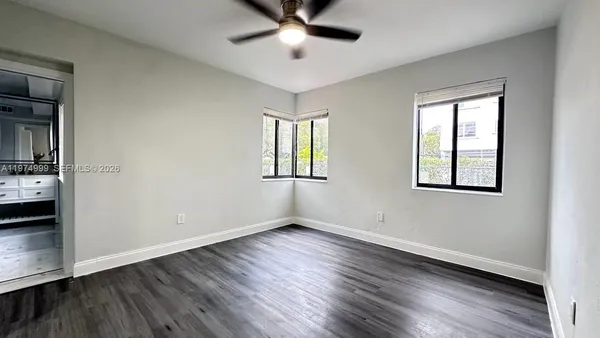 a view of an empty room with window and wooden floor