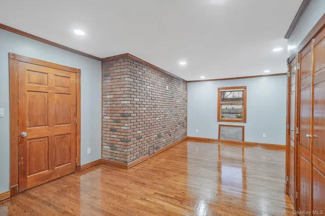 a view of an empty room with wooden floor and closet area
