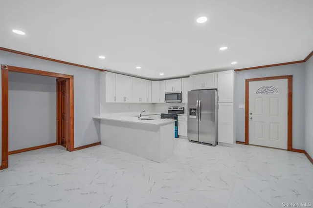 a large white room with stainless steel appliances granite countertop a couch and cabinets