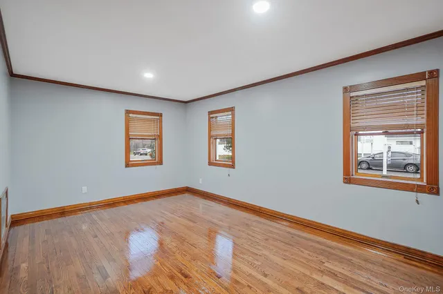 a view of an empty room with window and wooden floor
