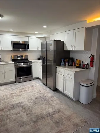 a kitchen with stainless steel appliances a stove a sink a refrigerator a microwave and cabinets