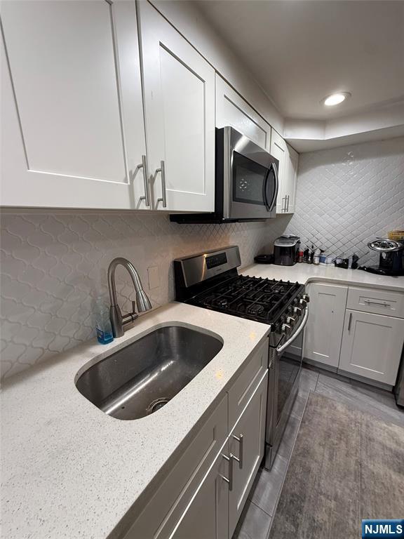 61 Sabina Street, Unit 1 Little Ferry, NJ 07643 - Photo 6 of 16 a kitchen with stainless steel appliances granite countertop a sink a stove and a microwave oven with cabinets
