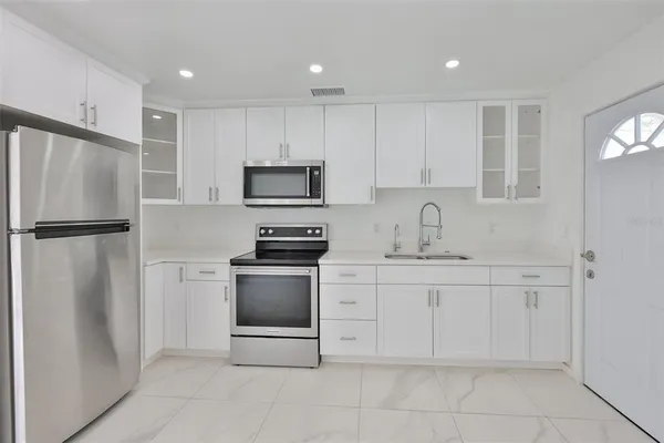 a view of a refrigerator in kitchen and an empty room