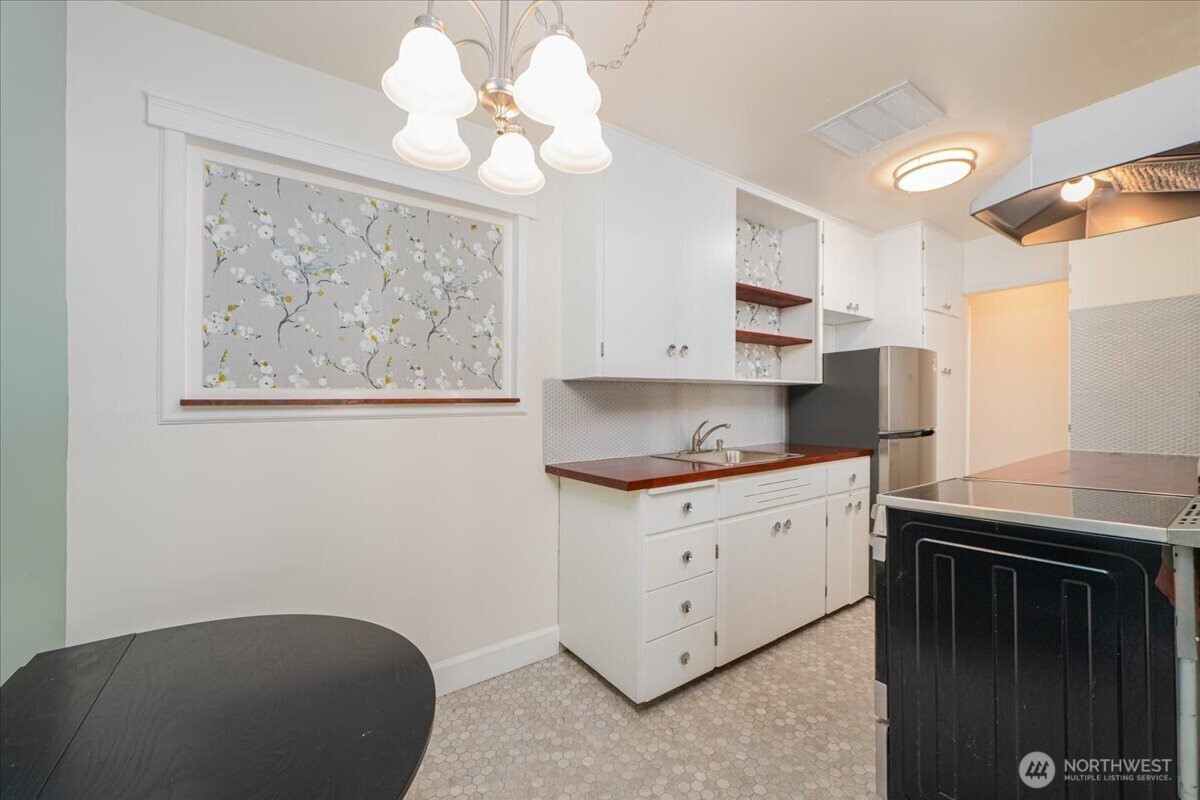 7 Harrison Street, Unit 20 Seattle, WA 98109 - Photo 7 of 27 a kitchen with stainless steel appliances granite countertop a sink a stove a microwave a dining table and chairs with wooden floor