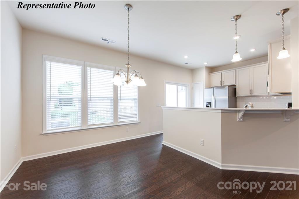 465 Hunters Dance Road, Unit 341 Fort Mill, SC 29708 - Photo 5 of 19 a view of a kitchen with kitchen island a sink wooden floor and a window