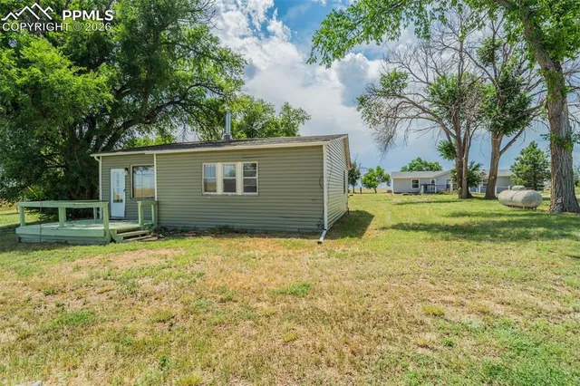 a view of a house with a yard and large tree