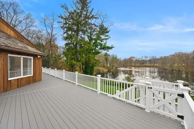 a view of a balcony with wooden floor and fence and a trees