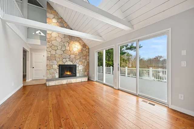 a view of an empty room with wooden floor and a fireplace