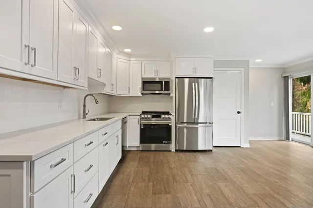 a kitchen with granite countertop white cabinets and stainless steel appliances