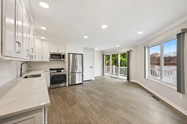 a large kitchen with stainless steel appliances granite countertop a large window a sink and a stove