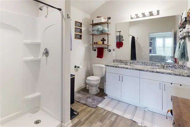 a spacious bathroom with a granite countertop sink a toilet and a shower